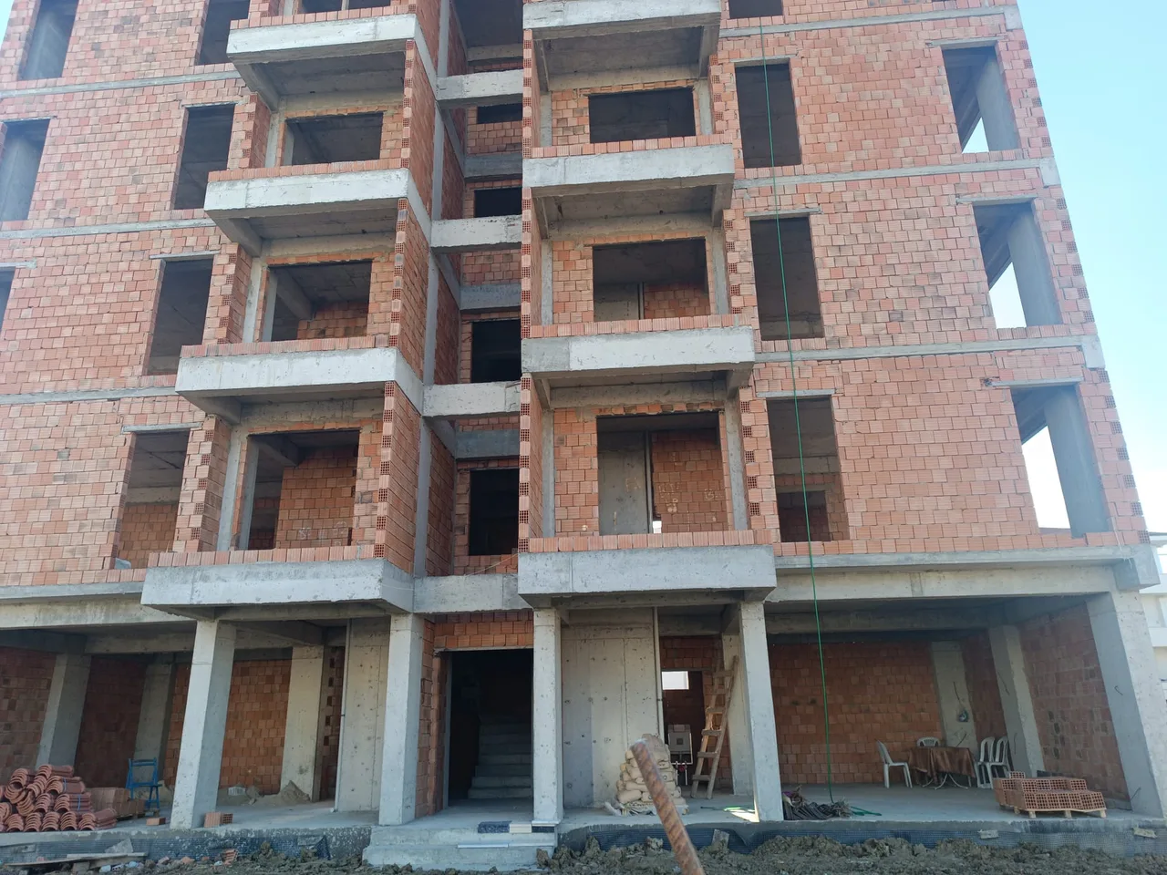 Tuğla duvarları ve beton balkonları açıkta, kaba yapı halindeki apartman