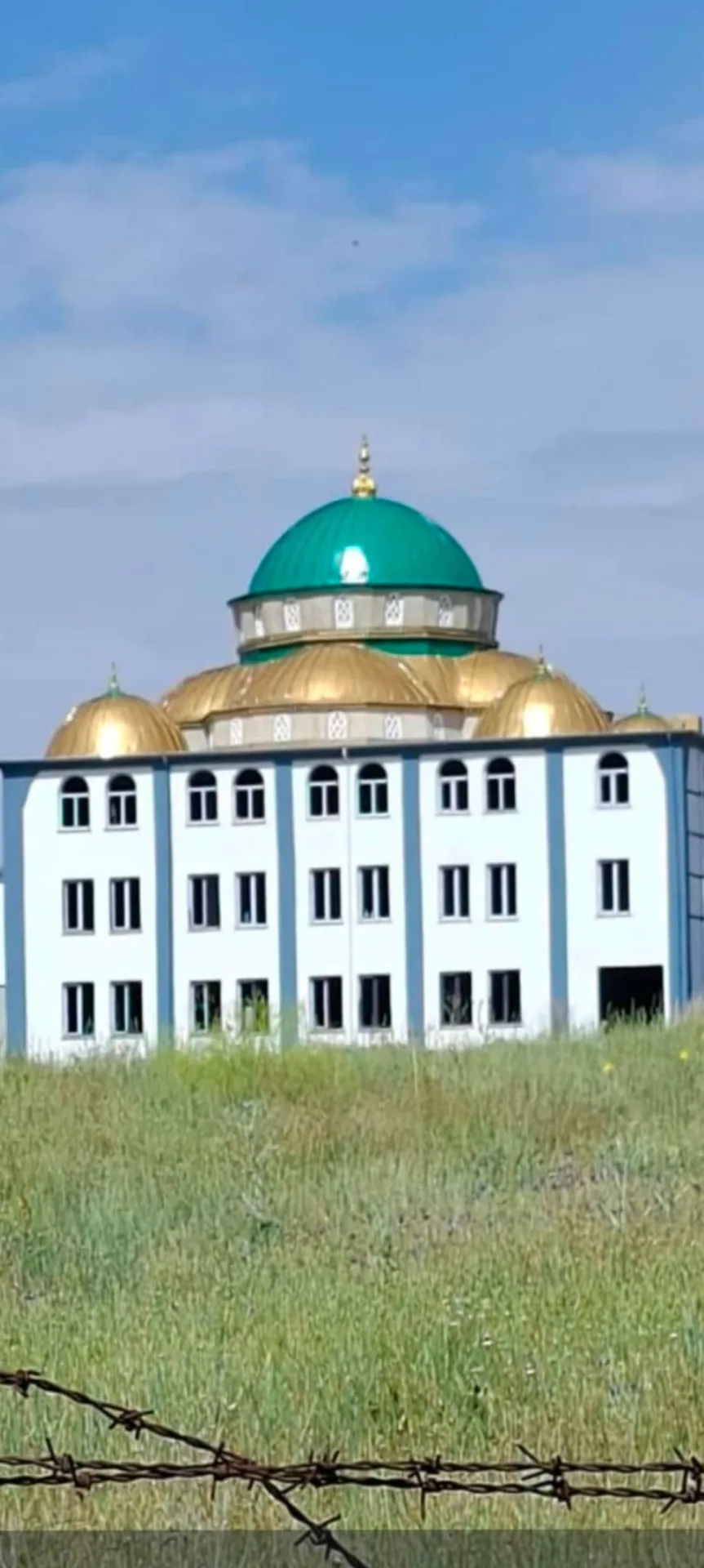 Dış cephesi tamamlanmış, yeşil ve altın kubbeli cami